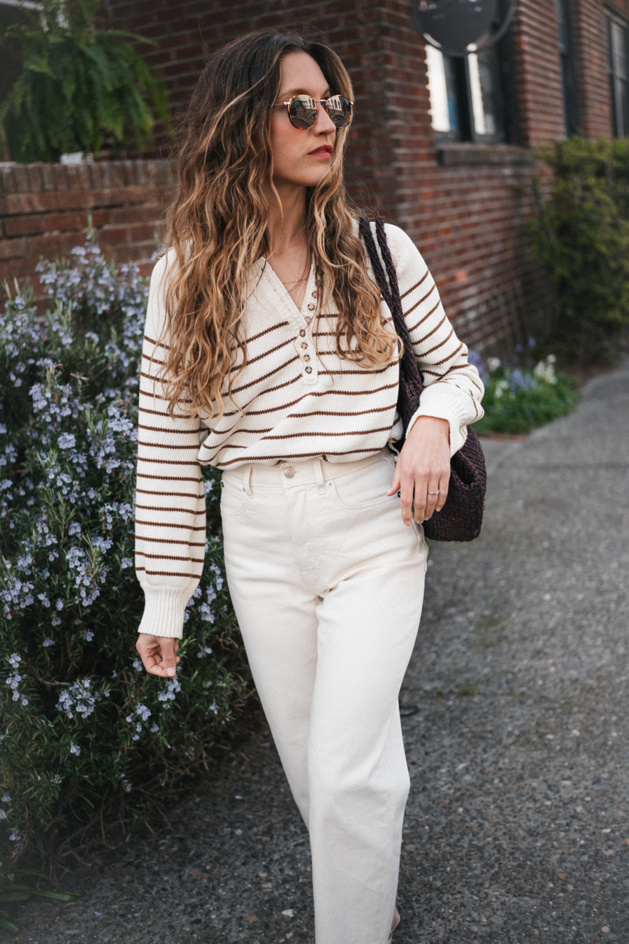 ashley wearing the Sézane Léontine Jumper with white denim, ivory sandals, and a brown woven tote bag