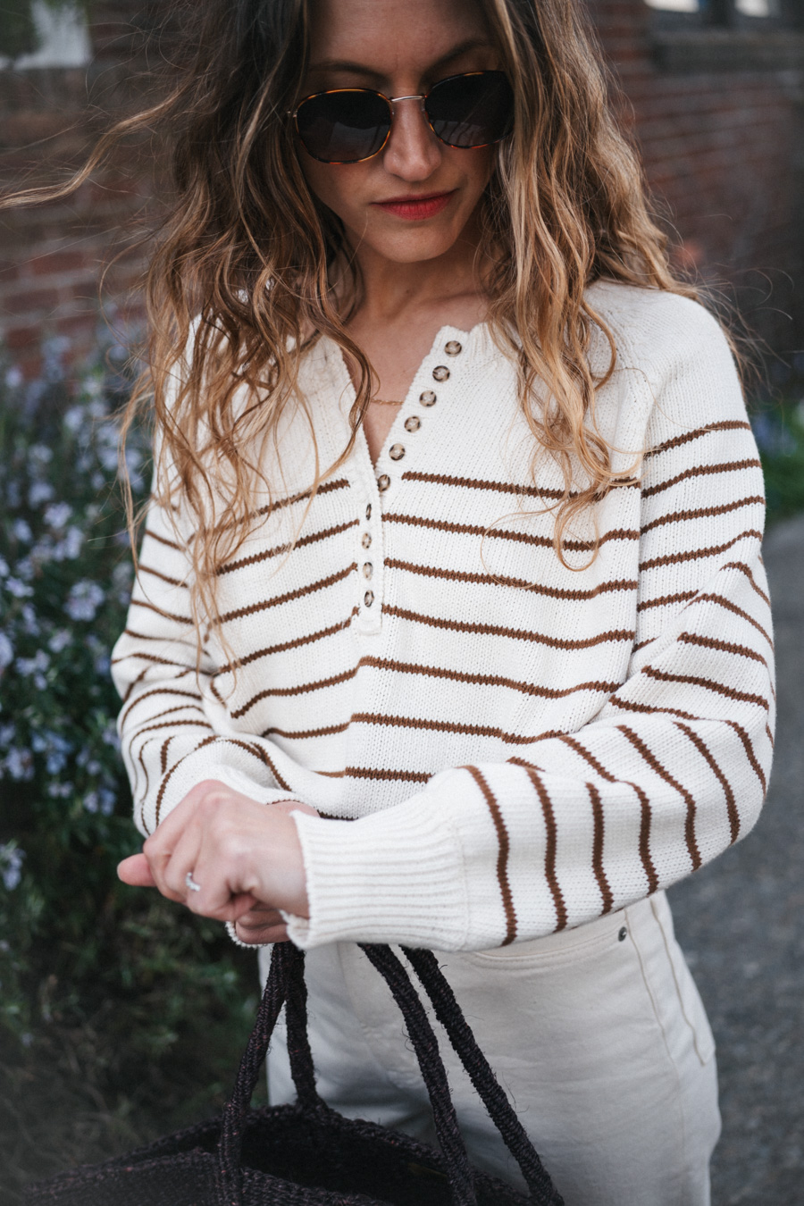 ashley wearing the Sézane Léontine Jumper with white denim, ivory sandals, and a brown woven tote bag