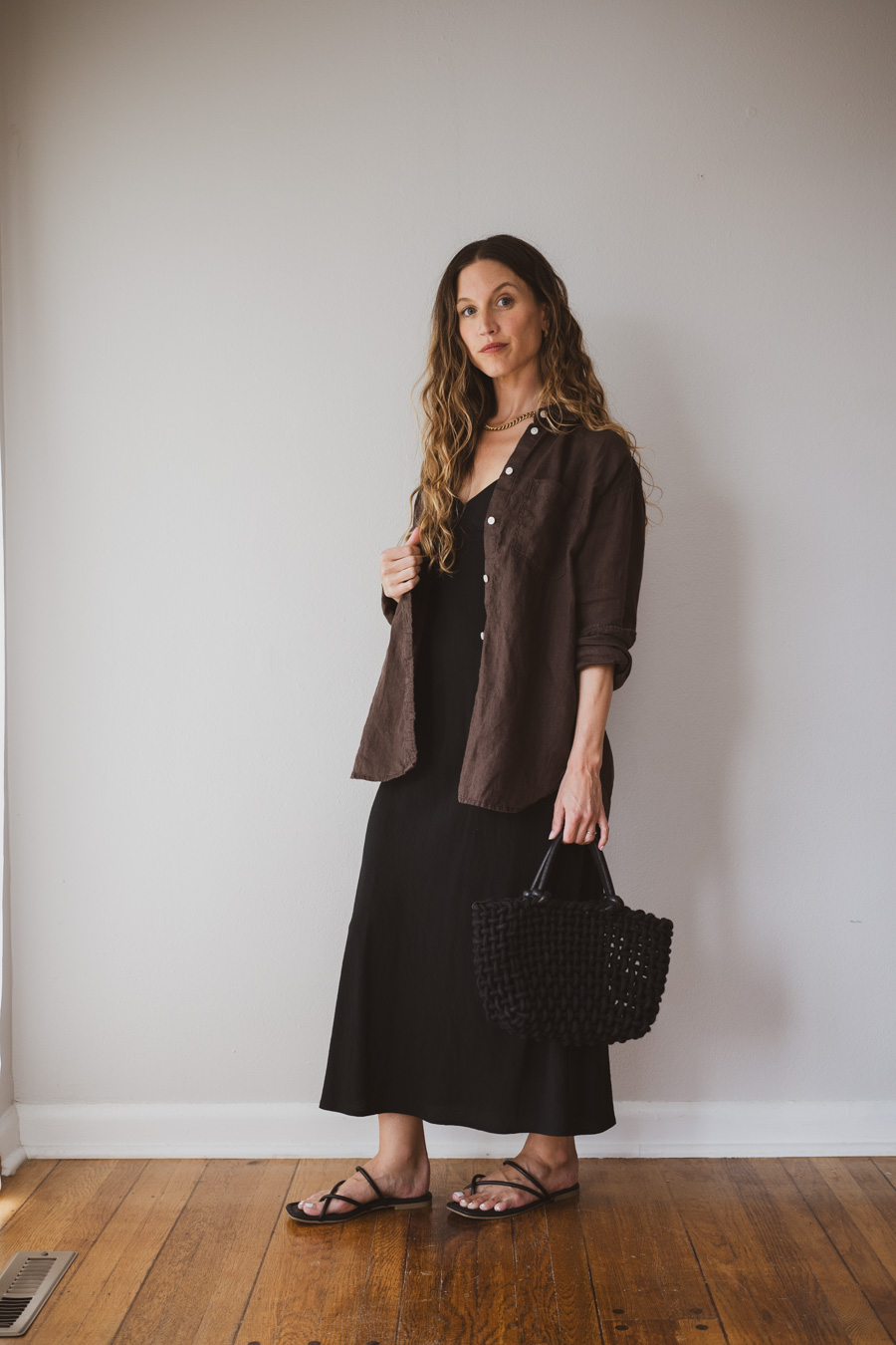 styling a linen set over a black slip dress with sandals and black woven handbag