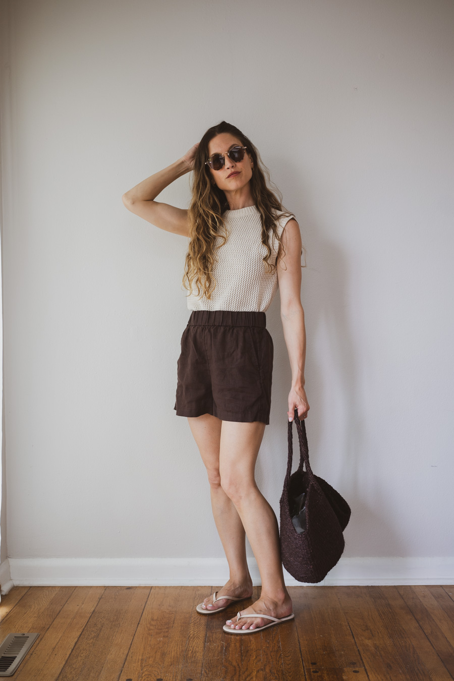 styling a linen set with a beige sweater tank, sandals, and woven tote bag