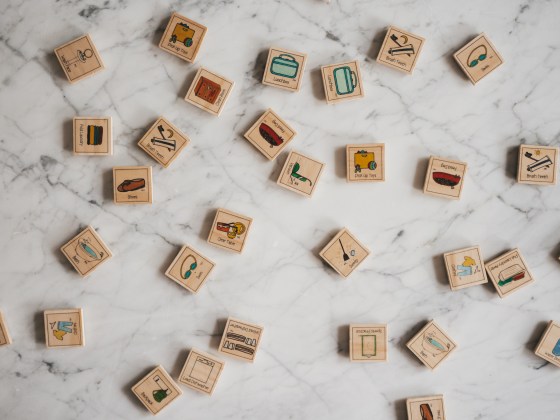 wood tiles with different chores pictured on them spread on a white marble table