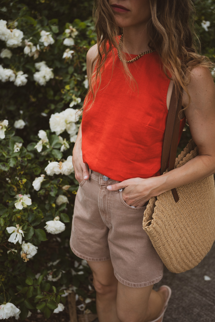 fourth of july outfit idea with a red tank, tan denim short, beige sandals, and a straw tote bag