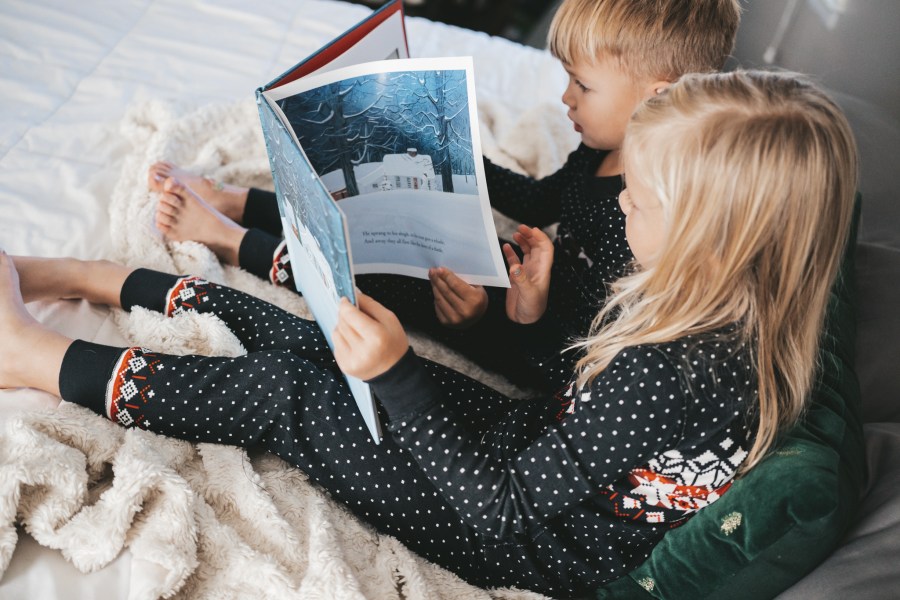 two kids in pajamas reading The Night Before Christmas 