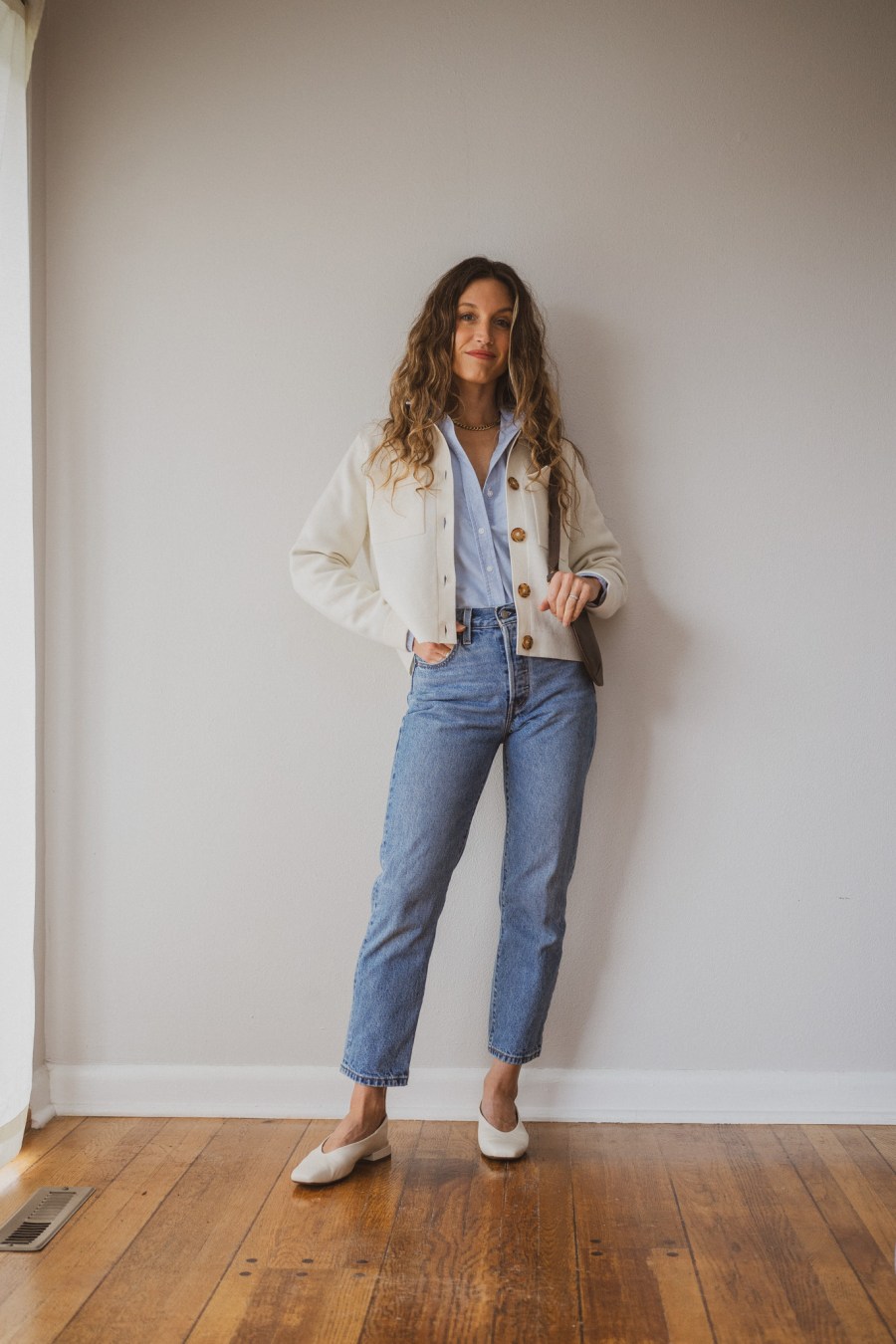 outfit with the Sézane Betty Cardigan with a blue button down layered underneath, straight cropped jeans, and white square toe ballet flats