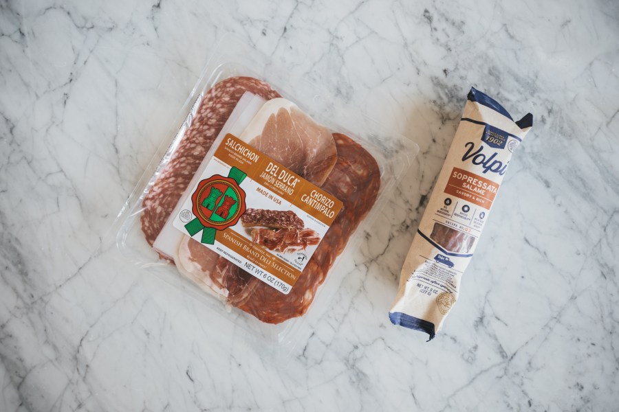 a white marble table with 2 packages of meats for a holiday charcuterie board