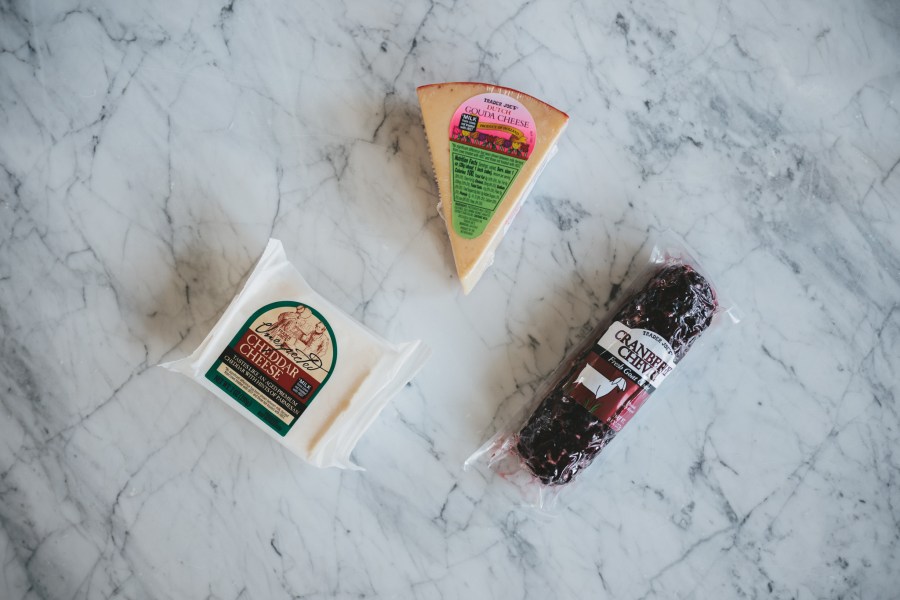 a white marble table with 3 different cheeses for a holiday charcuterie board