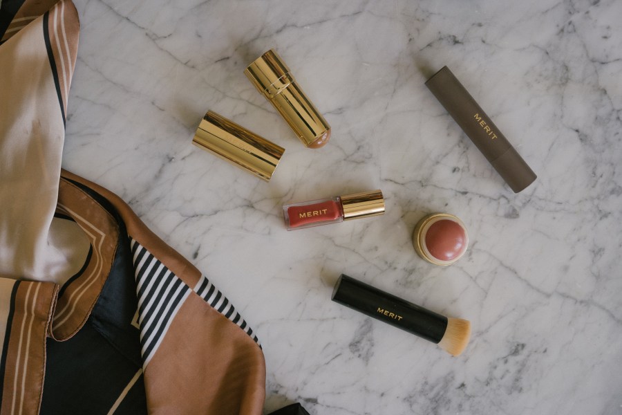 merit beauty products on a marble table with a black and beige patterned scarf