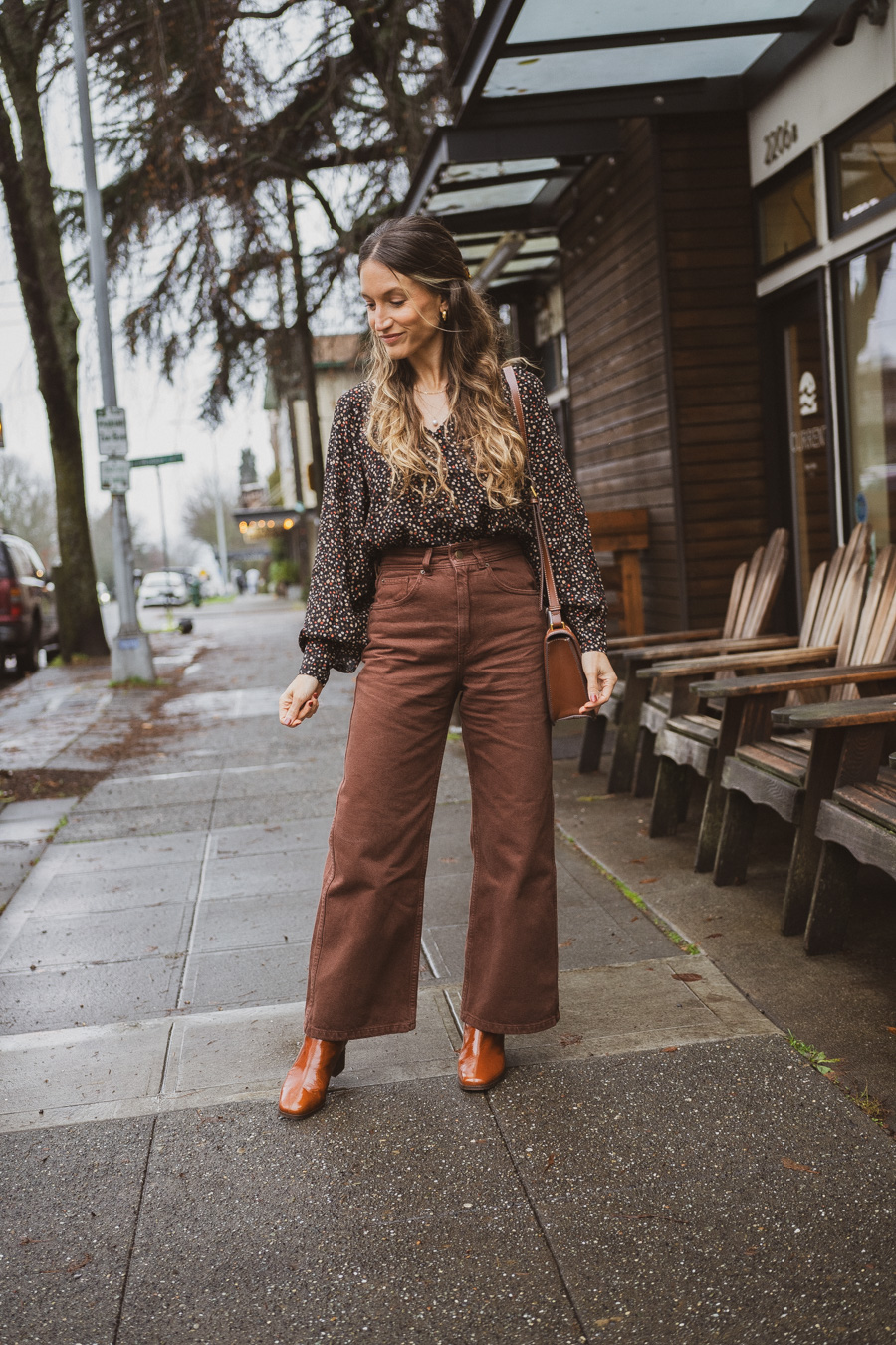 black and brown outfit with a black floral blouse, brown cropped pants, and polished camel boots