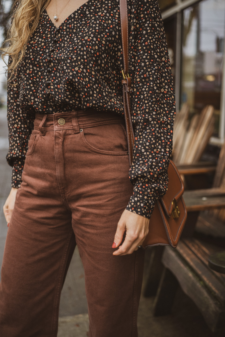 black and brown outfit with a black floral blouse, brown cropped pants, and polished camel boots