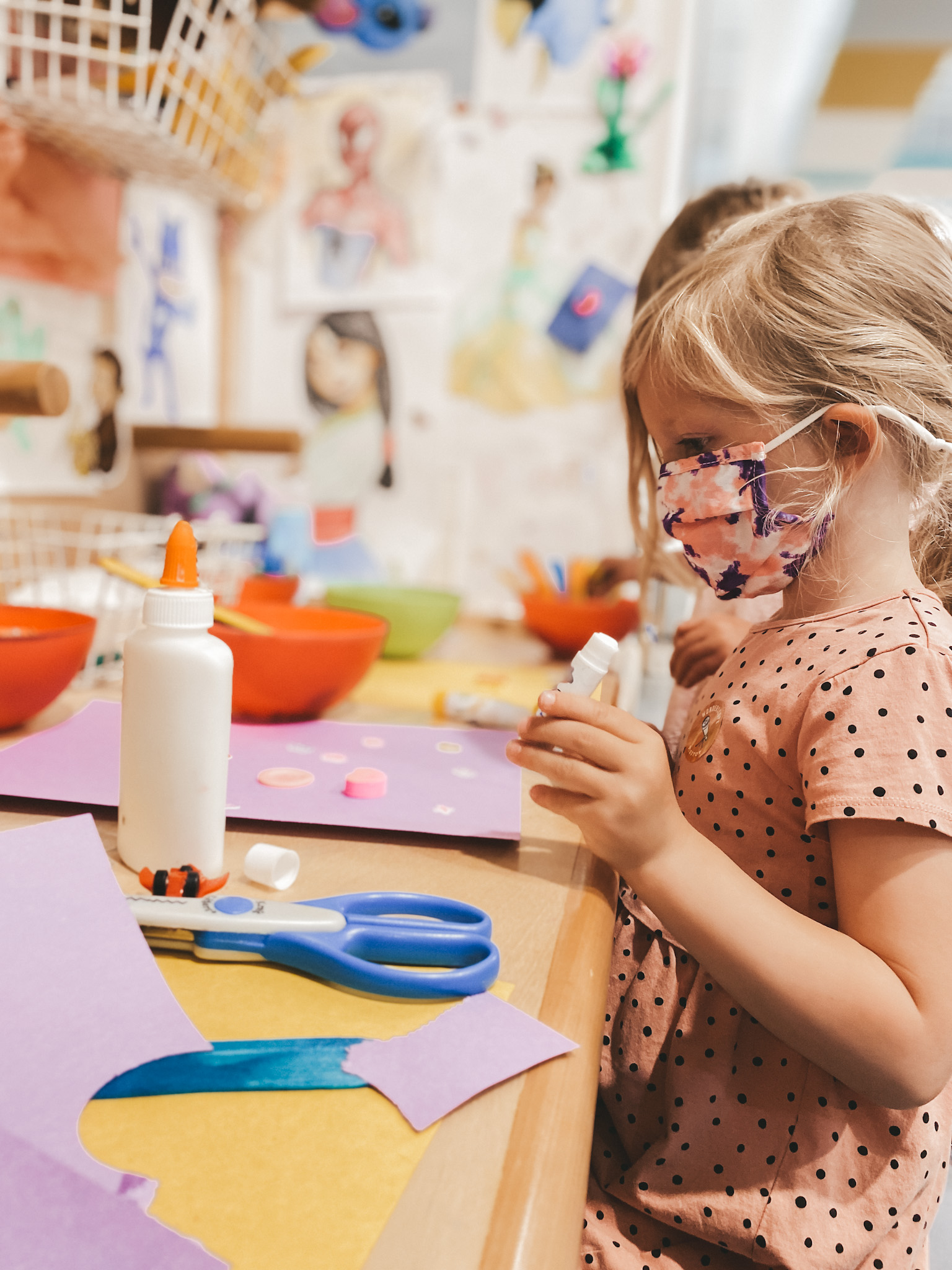 a little girl in a pink dress sitting at a table doing crafts at Wonderscope